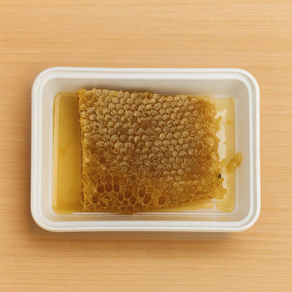 Honeycomb with honey in a white container on a wooden surface