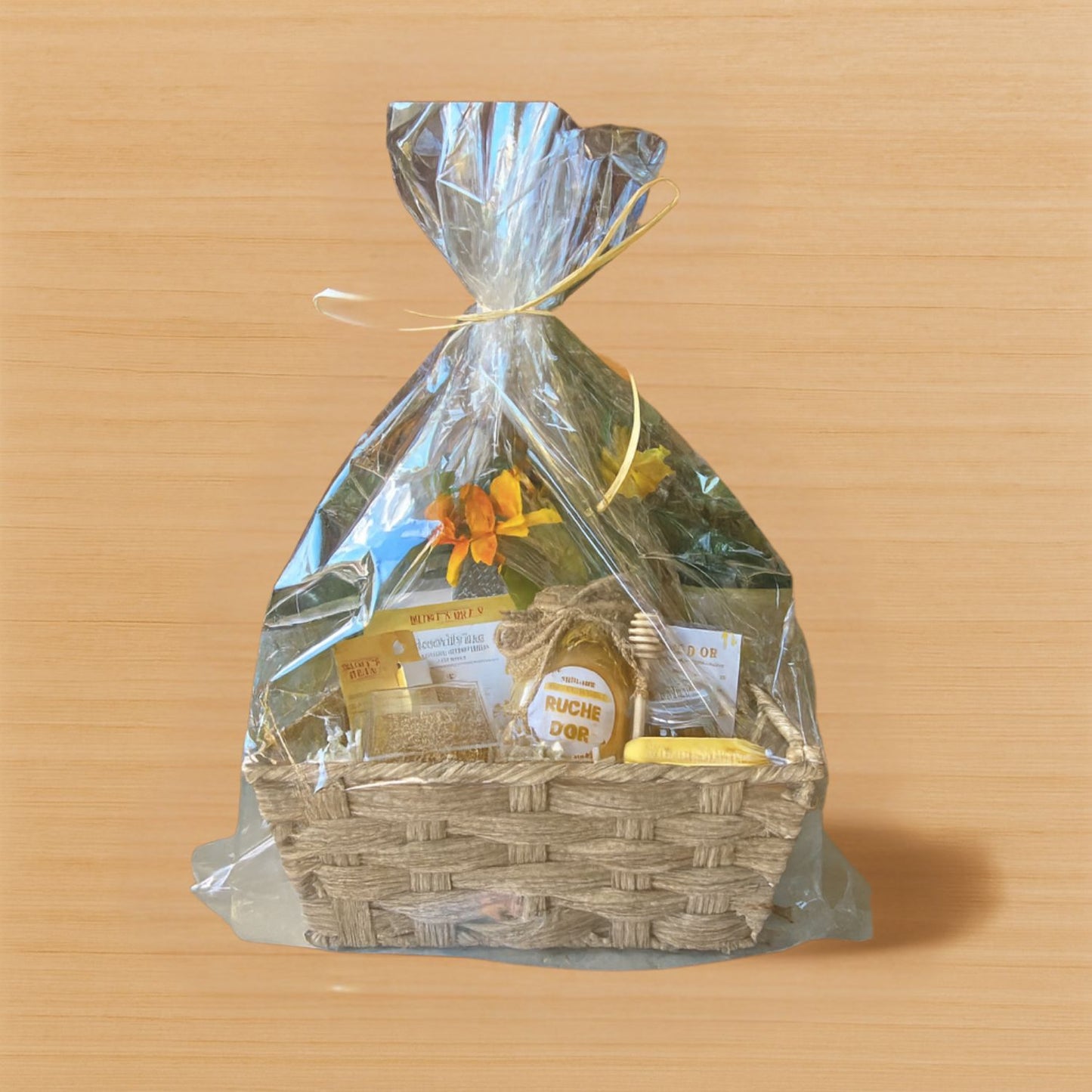 Gift basket wrapped in clear cellophane with a yellow ribbon on a wooden surface